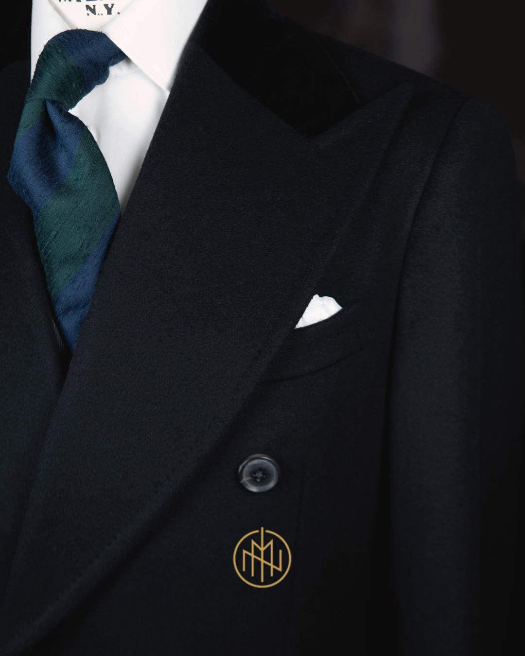 Rzemieślnicze stebnowanie w czarnym płaszczu na miarę - detal bez butonierki